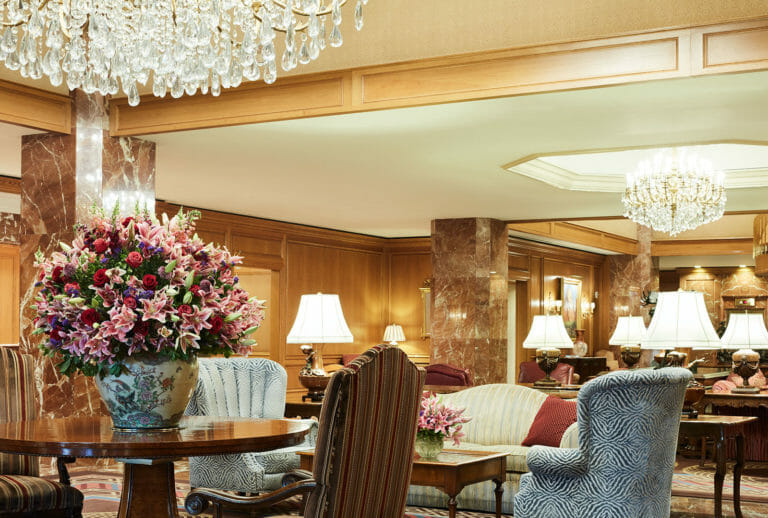 The Lobby entrance at Little America Hotel featuring large seating area, fireplace, large floral arrangement, front desk, and concierge.