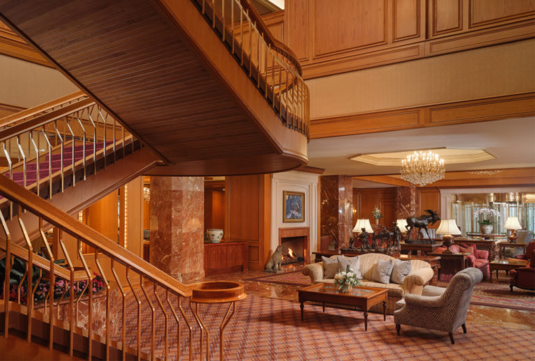 The Lobby entrance at Little America Hotel featuring large seating area, fireplace, large floral arrangement, front desk, and concierge.